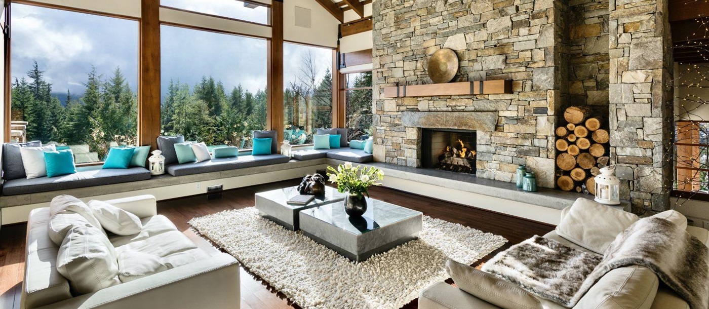 View from the comfortable lounge with fire place floor to ceiling windows at luxury private home The Belmont Estate in Whistler, Canada
