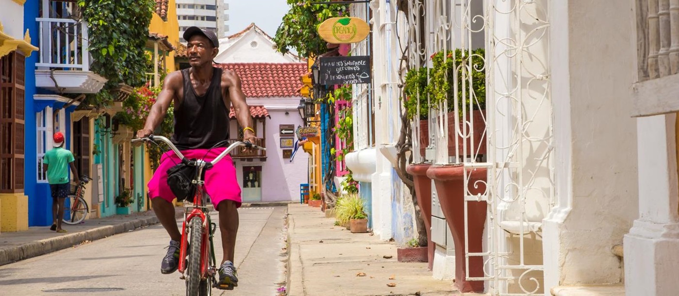 Local man cycling in the colourful streets of Cartagena, Colombia