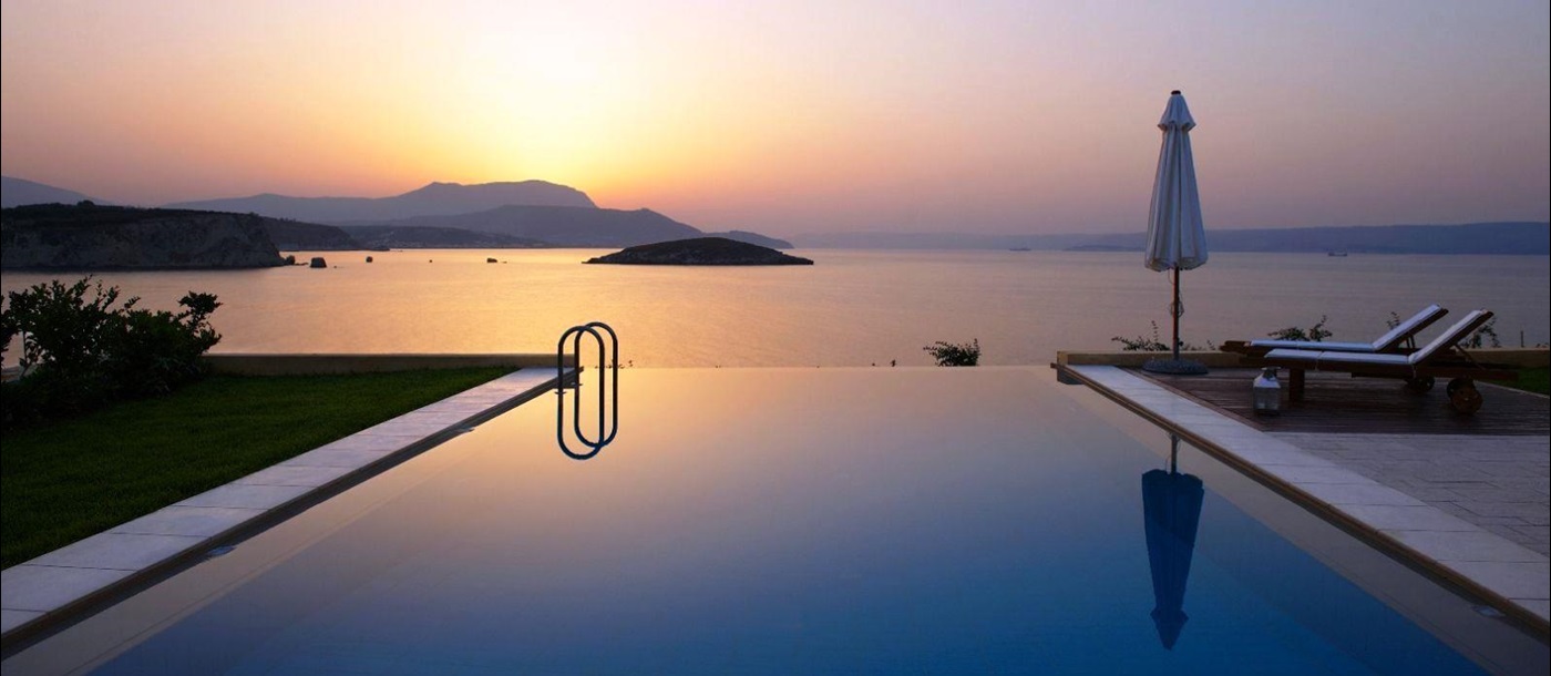 Swimming pool overlooking sea and mountains in the distance at sunset at villa anemos in crete