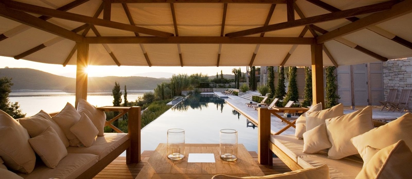 Lounge area by pool with sofas, coffee table and view of sea, sun loungers and patio at Villa Penelope on Corfu, Greece 