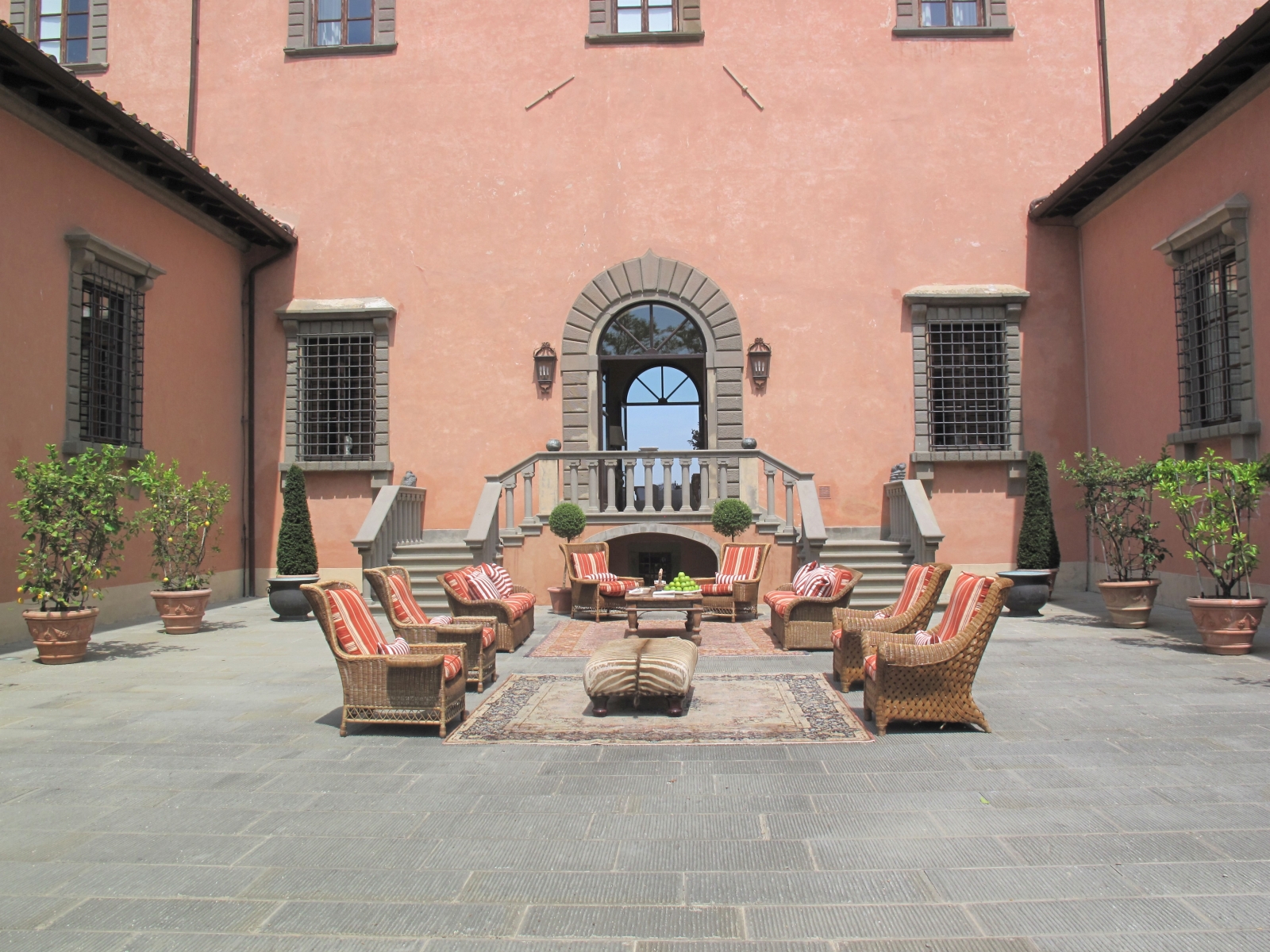 Courtyard with comfy chairs, citrus trees and stone stairs at Villa Machiavelli in Tuscany, Italy