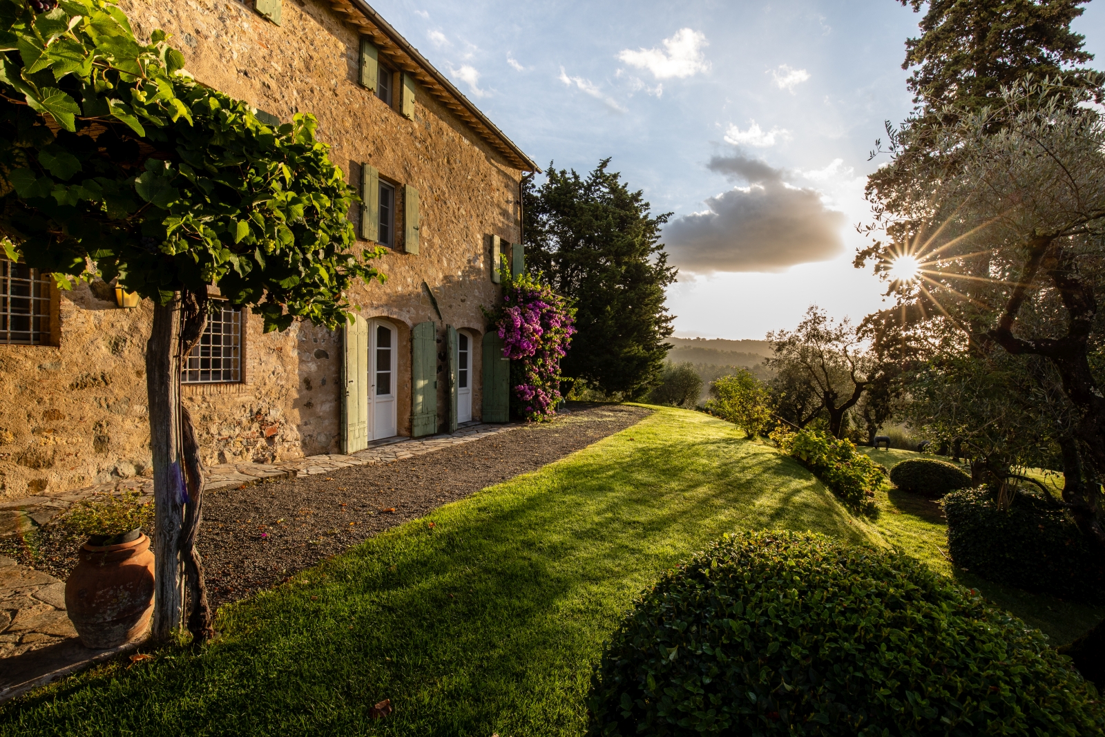 Exterior of villa with vines, flowers and grass at Villa Ortensia in Tuscany, Italy