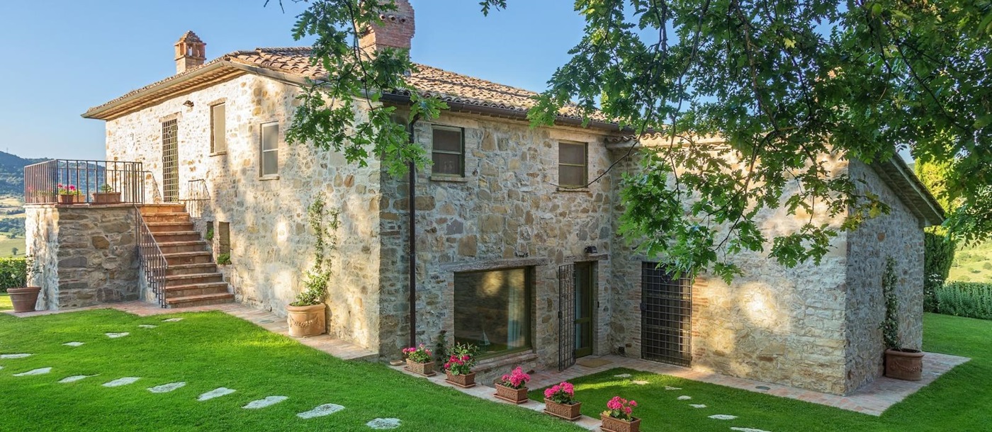 Exterior shot of villa and garden with flowers, plants and trees at Il Coccinella in Tuscany, Italy