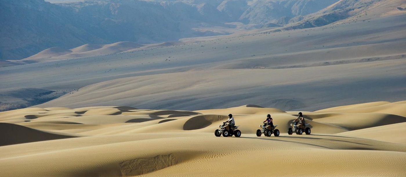  Guests exploring the dunes on a quad biking trip during a stay at luxury lodge Serra Cafema in Kakaoland, Namibia