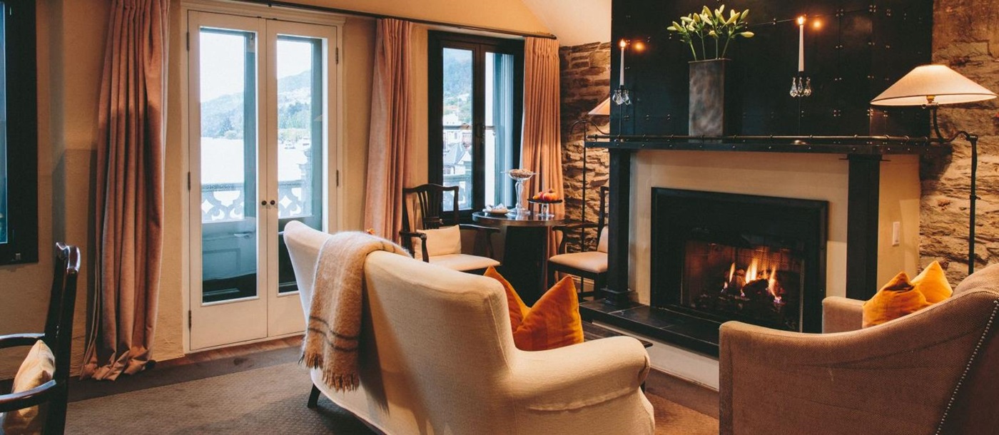Eichardt's Private Hotel New Zealand suite with a glowing fire in the fireplace and a sofa