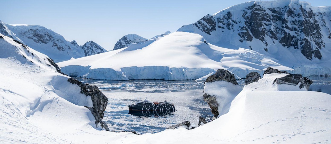 Distant view of the Magellan Explorer in Antarctica surrounded by snowy landscapes
