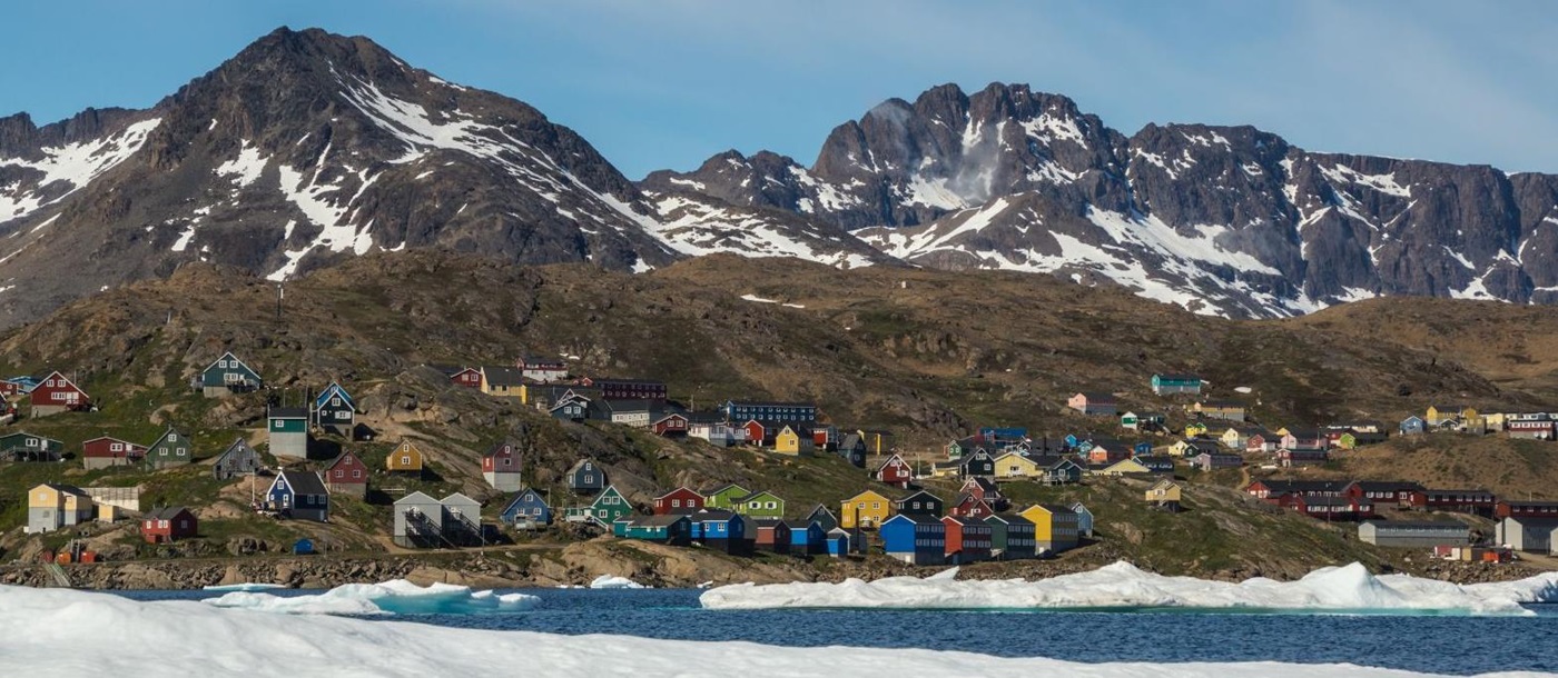 A small town with colourful houses in Greenland facing the water and floating ice