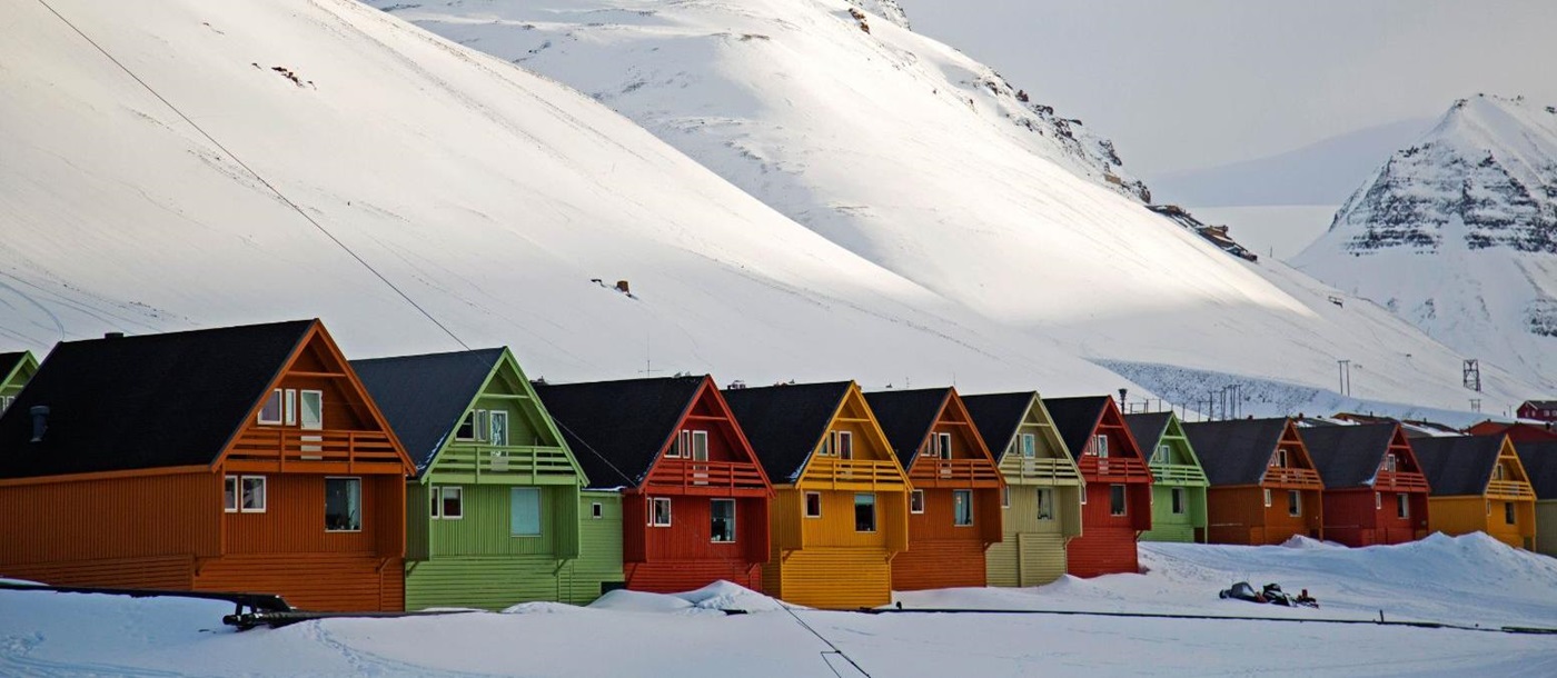 Colourful painted huts in front of snow covered mountains in Longyearbyen Norway