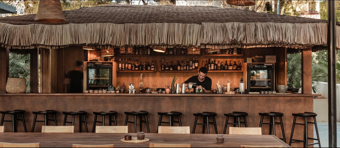 Bartender working at a straw-roofed bar at luxury resort OKU Ibiza