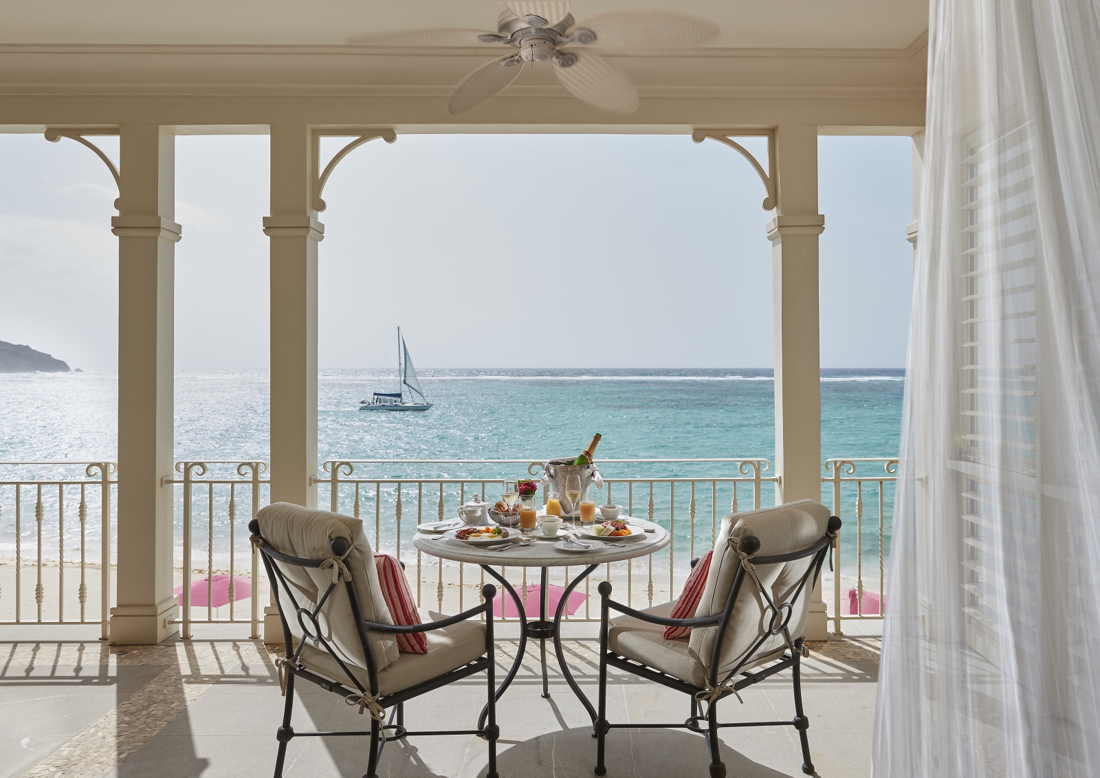 two chairs and a bottle of champagne on a balcony overlooking the ocean