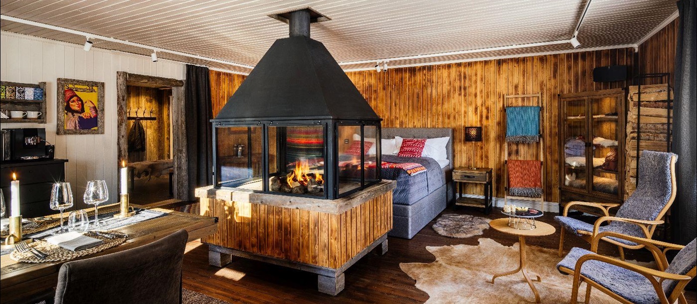 Cosy bedroom with indoor fireplace in luxury Loggers Lodge hotel in Sweden
