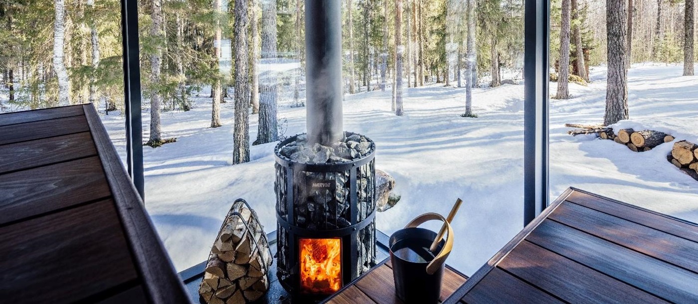 Interior view of private sauna with forest and snow views at luxury Loggers Lodge hotel in Sweden