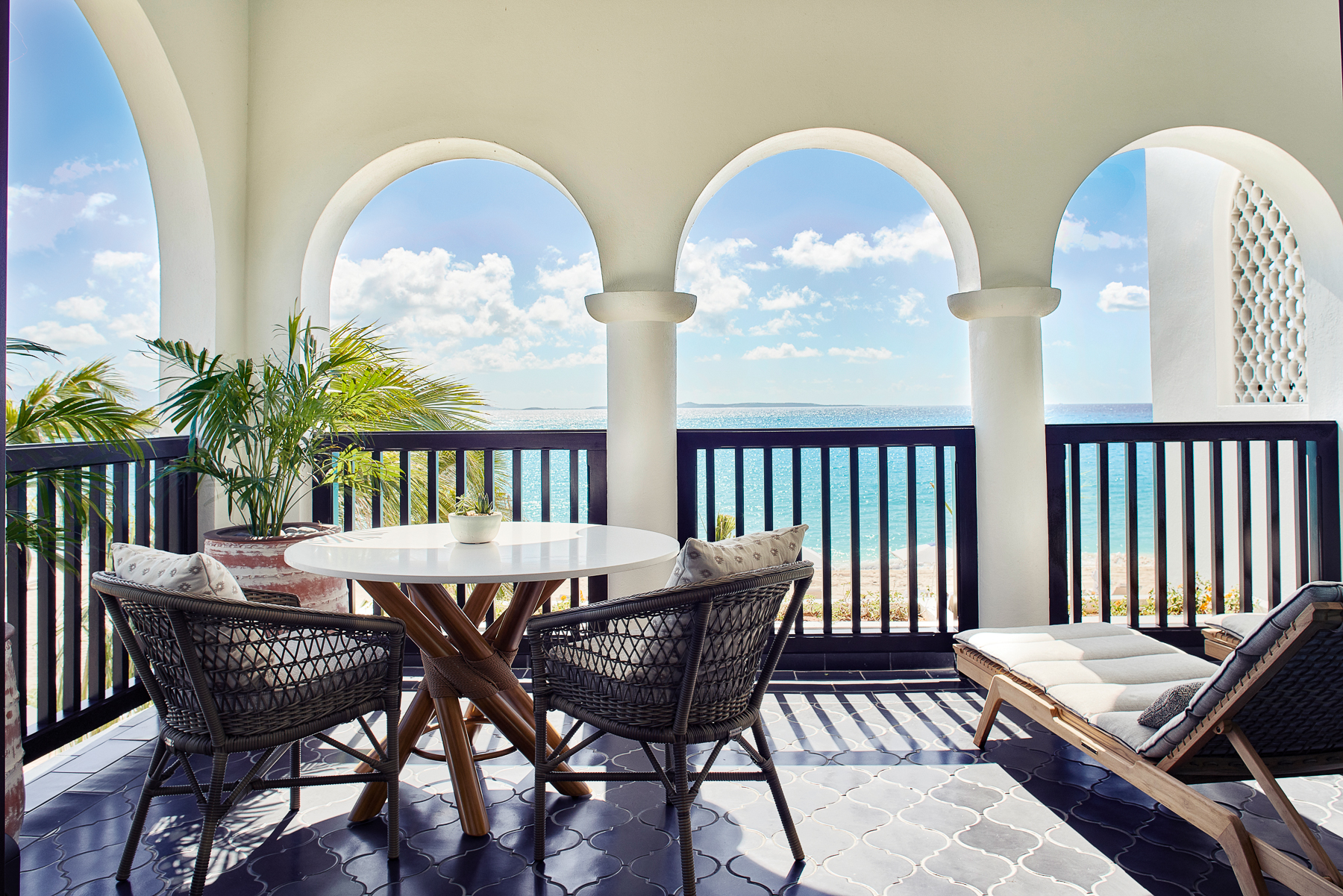 Balcony terrace with seating and views of the Caribbean Ocean from Belmond's Cap Juluca resort in Anguilla