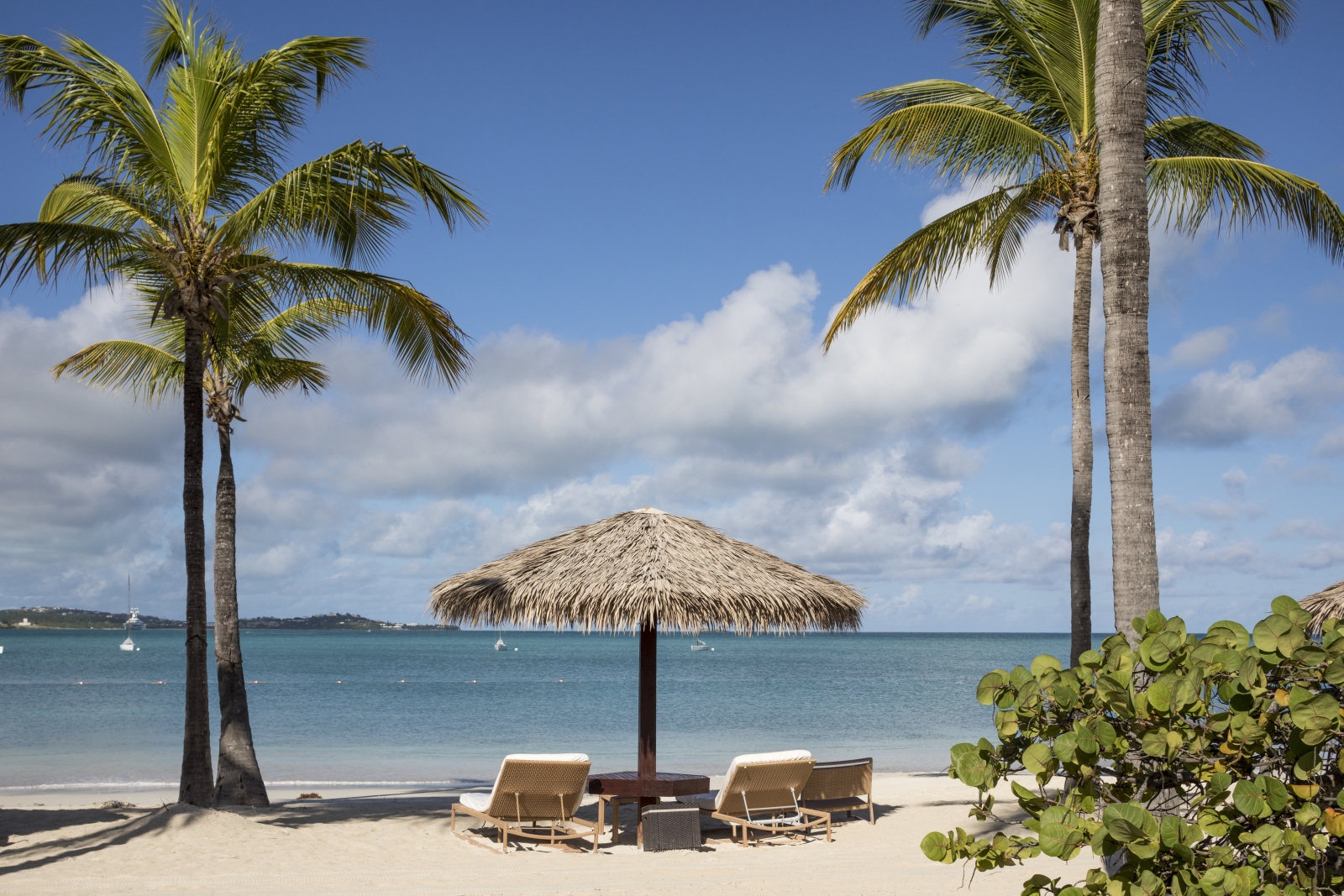 Two sun loungers with umbrella on a white-sand beach in Antigua