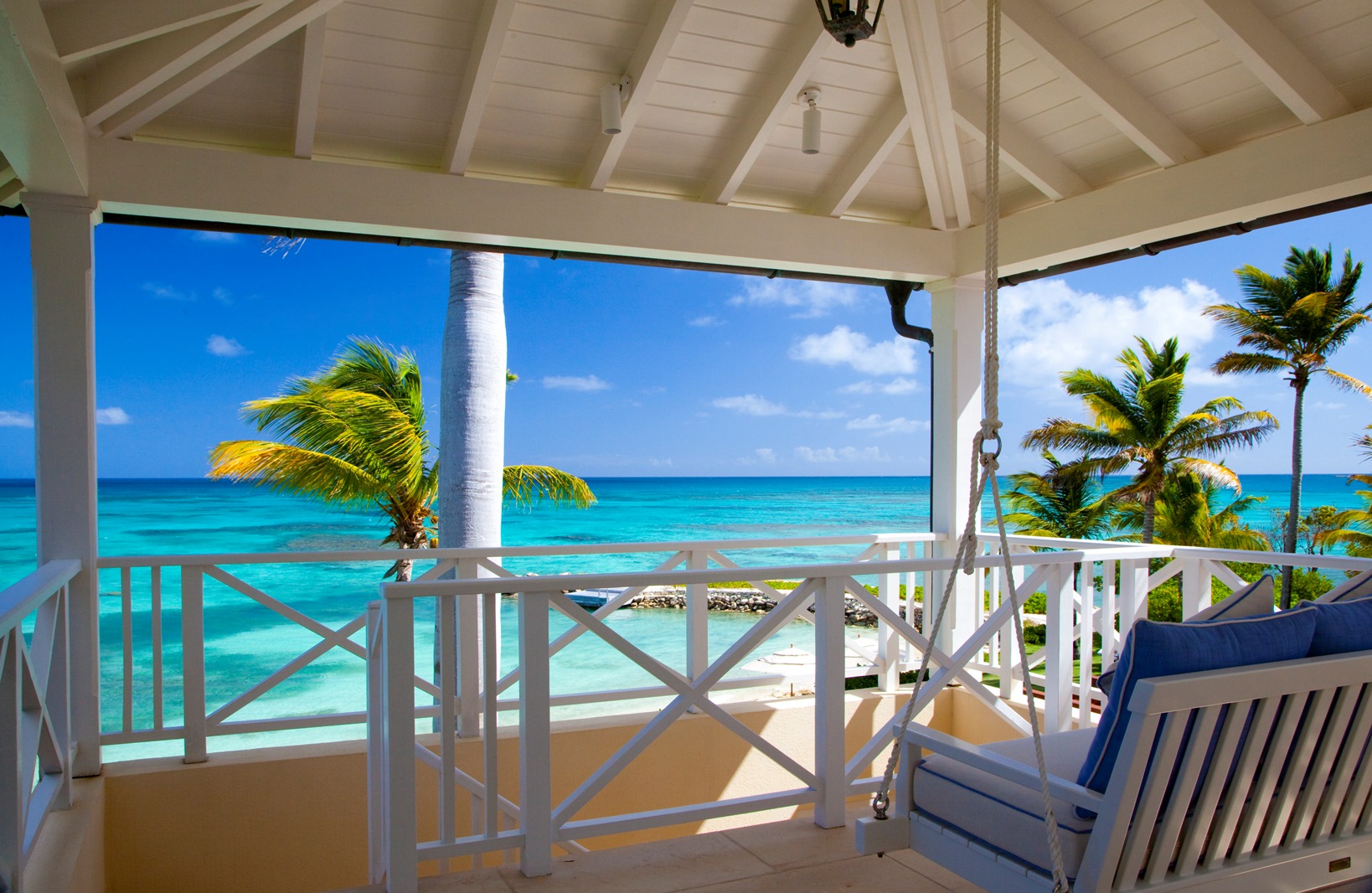 A terrace with ocean view and palm trees at Frangipani, Antigua