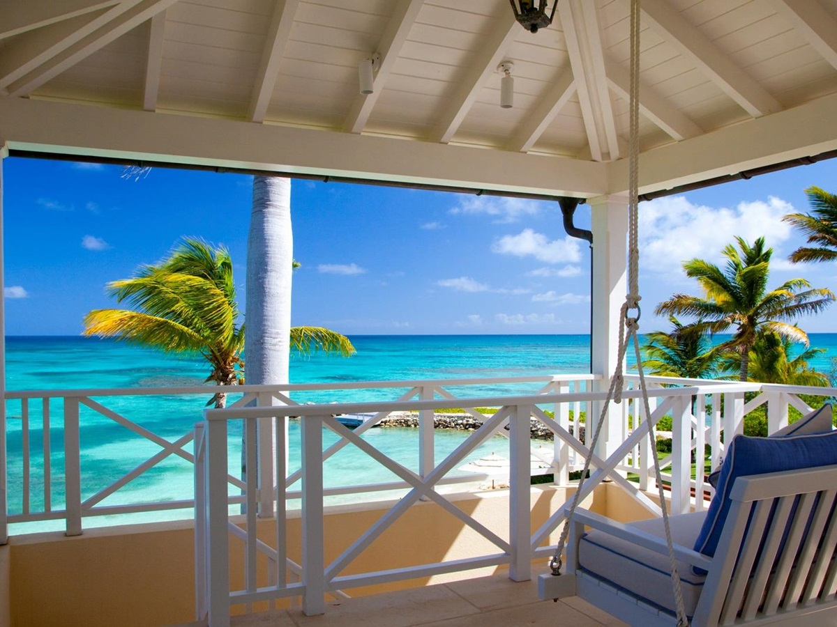 A terrace with ocean view and palm trees at Frangipani, Antigua