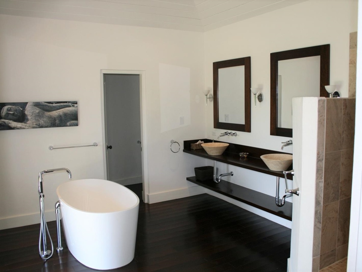 Bathroom with bath, double sinks, mirrors and artwork at The Hill Club in Antigua, the Caribbean