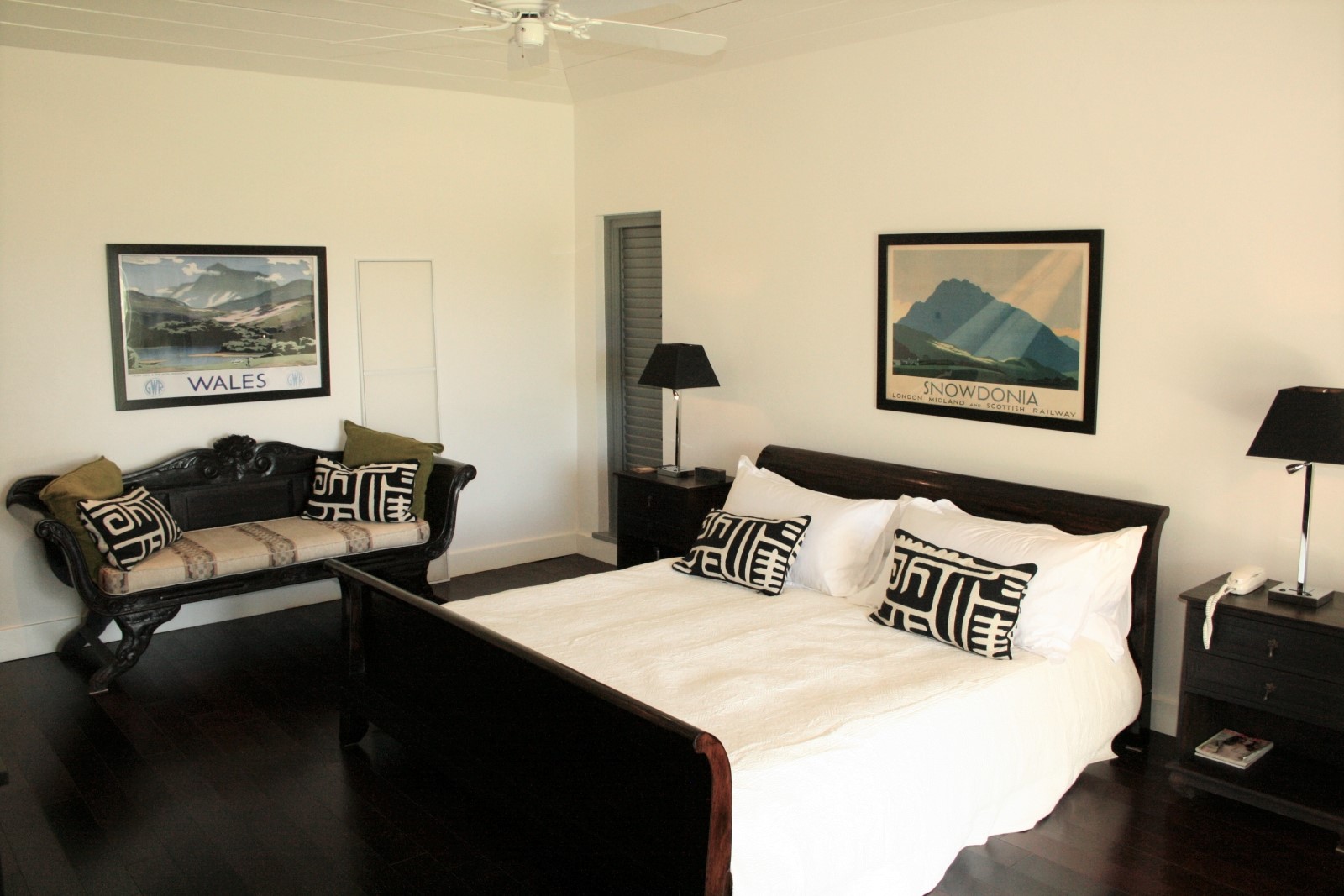 Bedroom with double bed, bedside tables, lamps, sofa and vintage artwork at The Hill Club in Antigua, the Caribbean