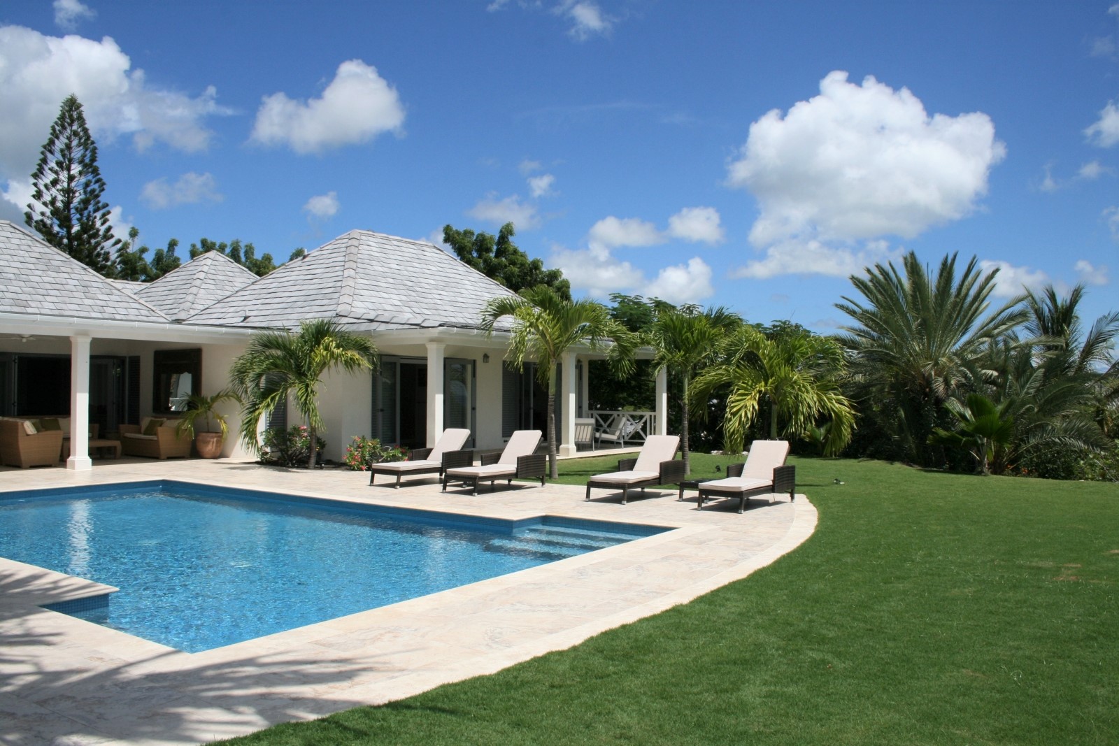 Garden and pool area with sun loungers and palm trees at The Hill Club in Antigua, the Caribbean