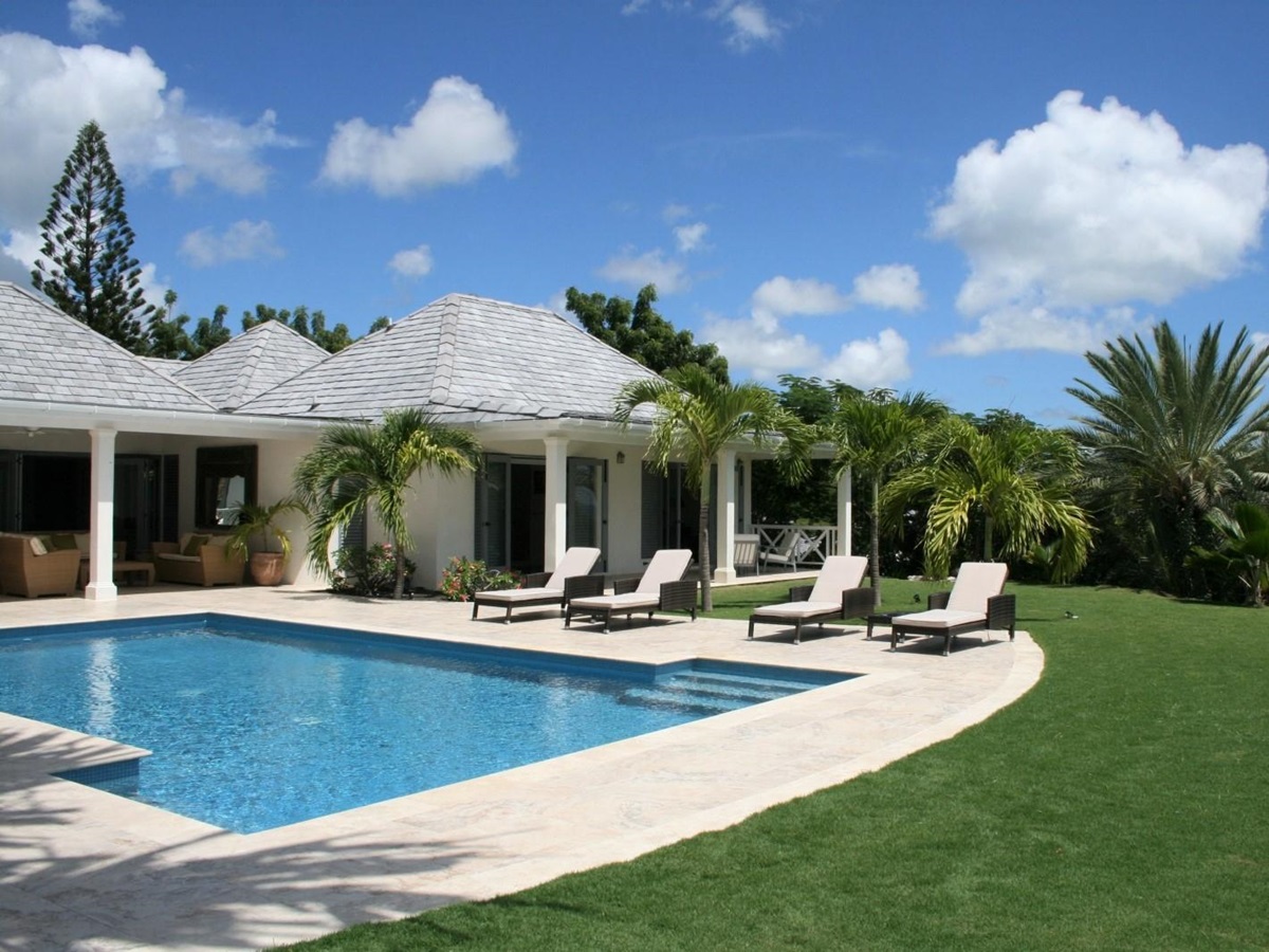 Garden and pool area with sun loungers and palm trees at The Hill Club in Antigua, the Caribbean