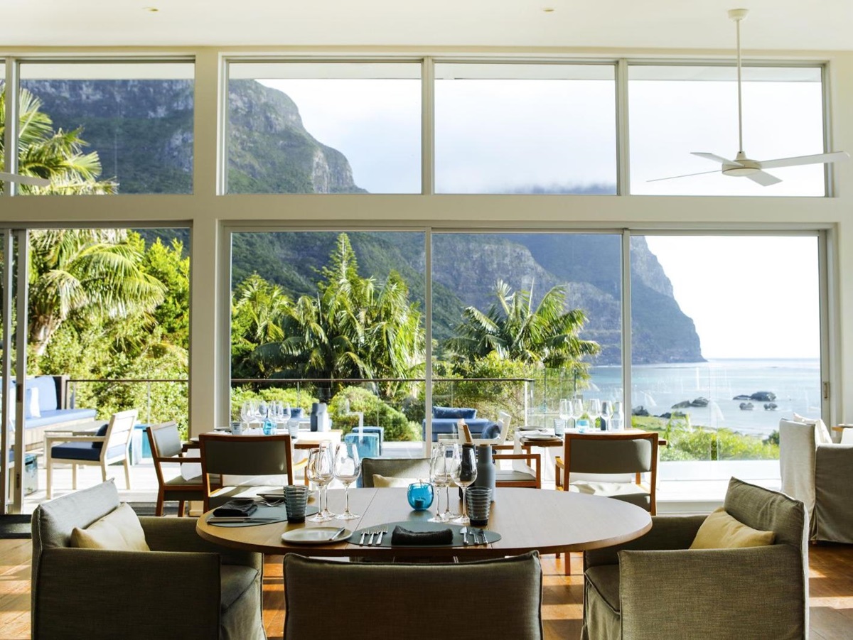 bright and sophisticated dining area with floor to ceiling windows looking out onto Lord Howe Island and clear blue seas in luxury Capella Lodge in Australia