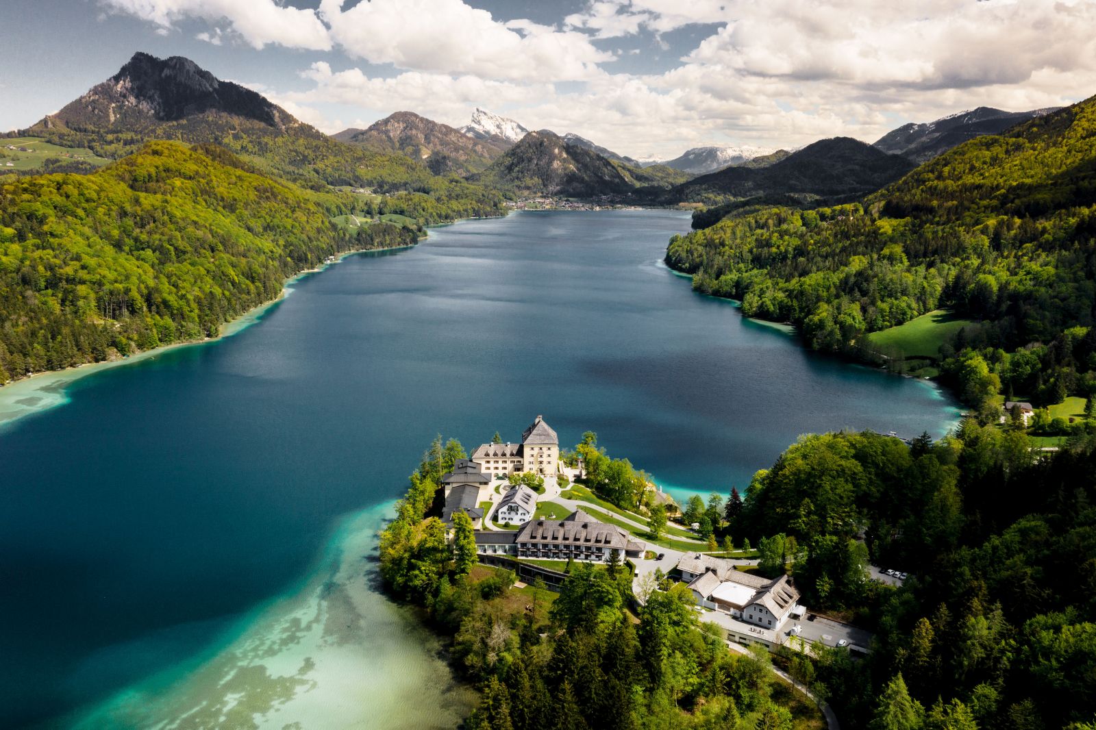 View of the Schloss Fuschl hotel in Austria with backdrop of lake and mountains