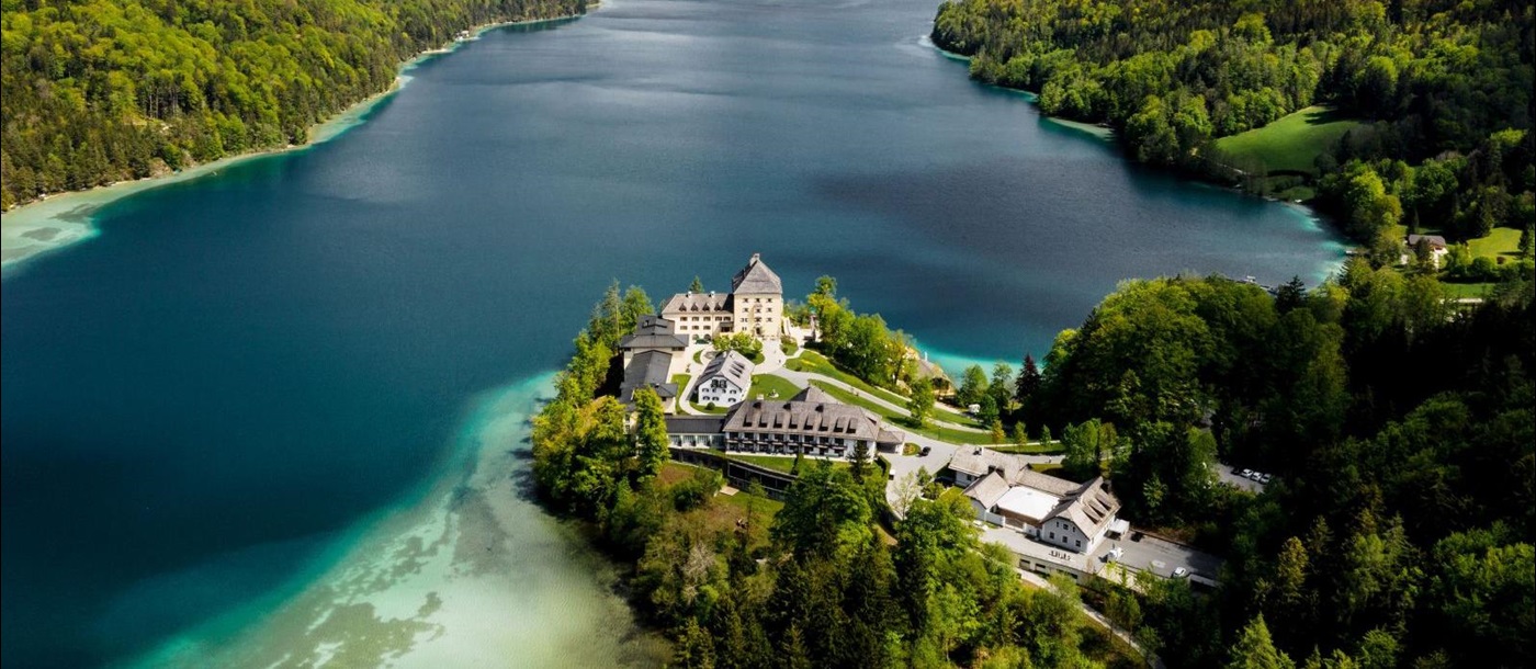 View of the Schloss Fuschl hotel in Austria with backdrop of lake and mountains