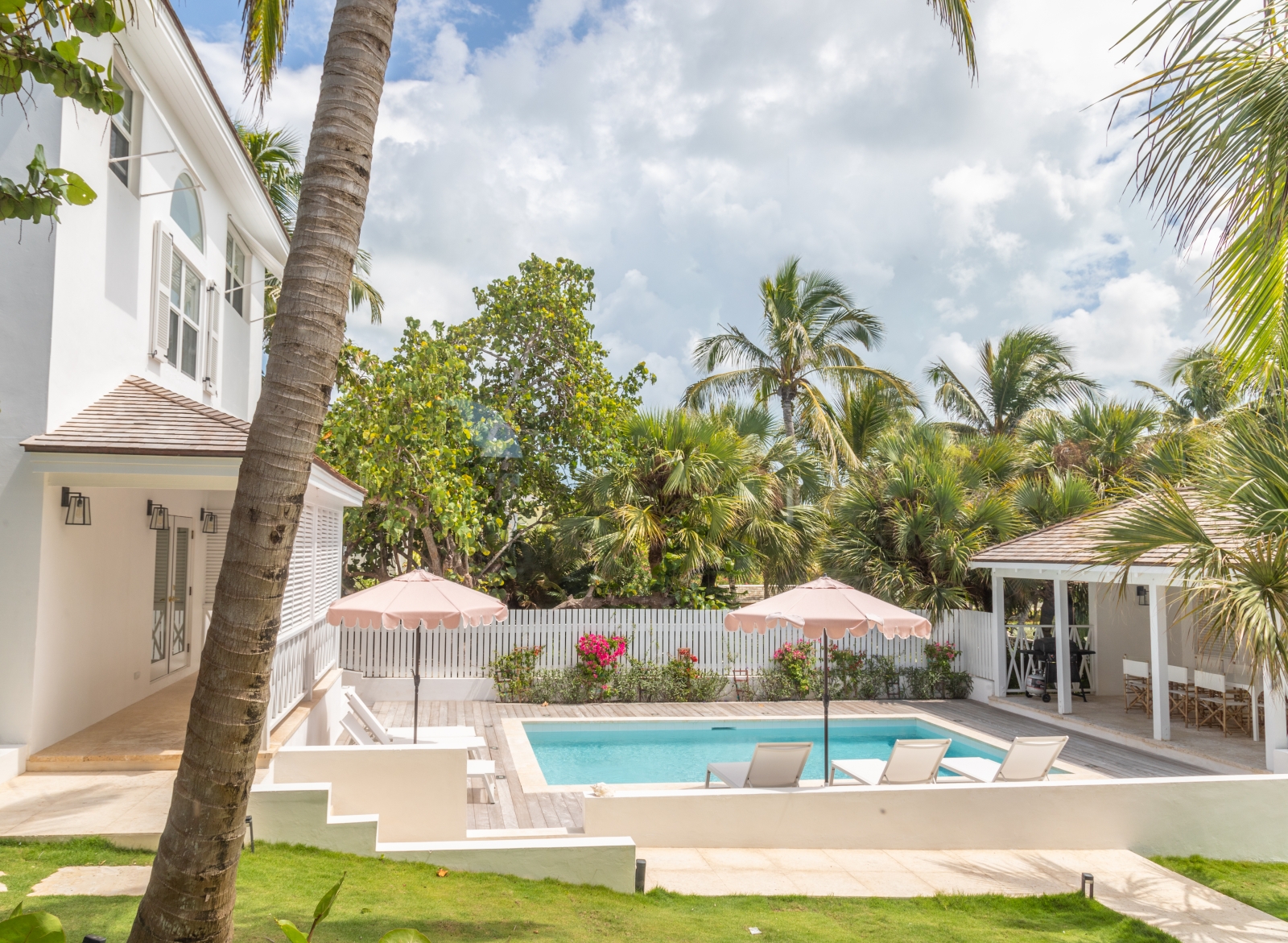 Garden with pool, sun loungers, umbrellas and pool house at Sea Siren in the Bahamas, Caribbean