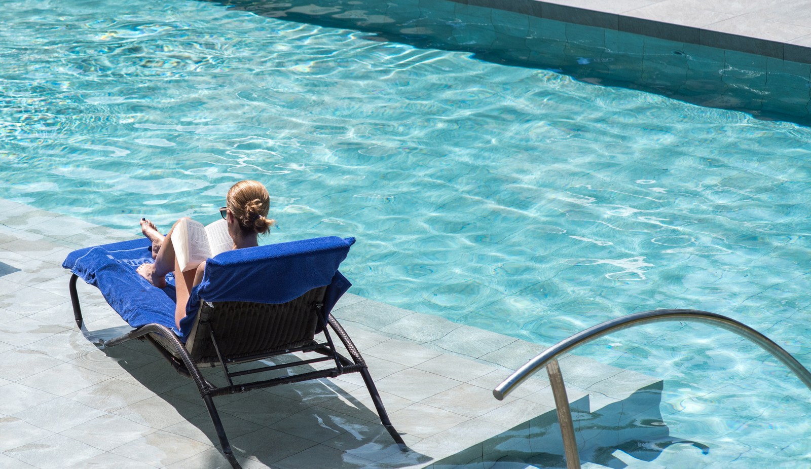 A woman reading a book at the swimming pool of the Sandpiper, Barbados