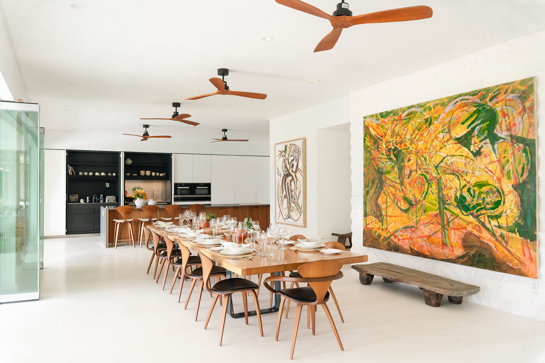 Dining room with long dining table, artwork and fans on the ceiling at Godings Beach House in Barbados