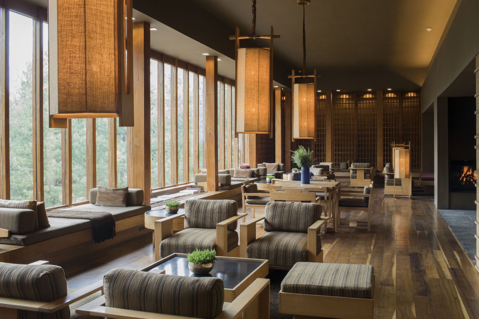 Comforting lounge area with floor to ceiling windows and indoor fireplace at luxury hotel Amankora Paro in Bhutan