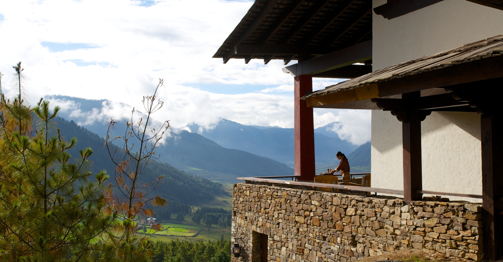 Woman stands on balcony looking at mountain view