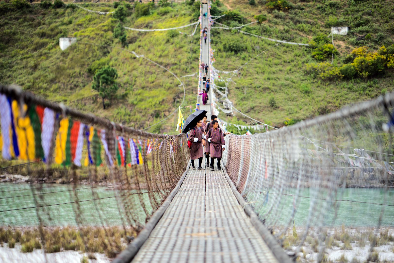 Locals walk towards camera on a bridge crossing the river