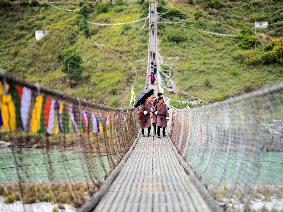 Locals walk towards camera on a bridge crossing the river