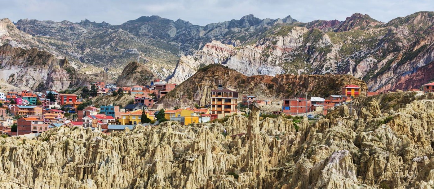 Buildings in La Paz, Bolivia with rock formations in the foreground and mountains in the background 