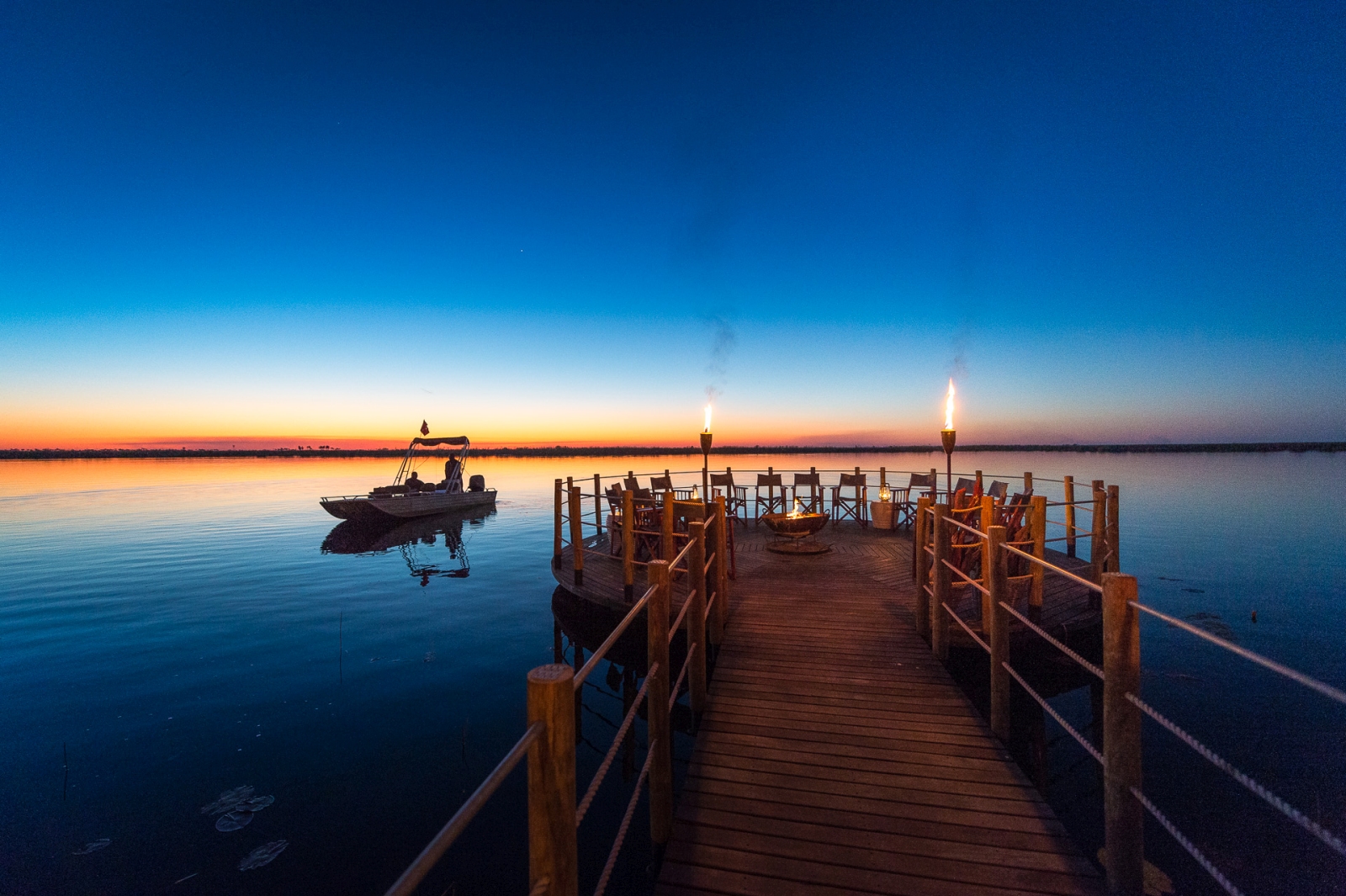 Cosy seating on a jetty with campfire at sunset at DumaTau in Botswana
