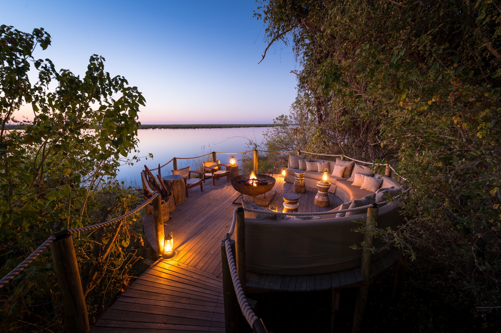 Cosy seating on a jetty with campfire at sunset at DumaTau, a luxury camp in Botswana
