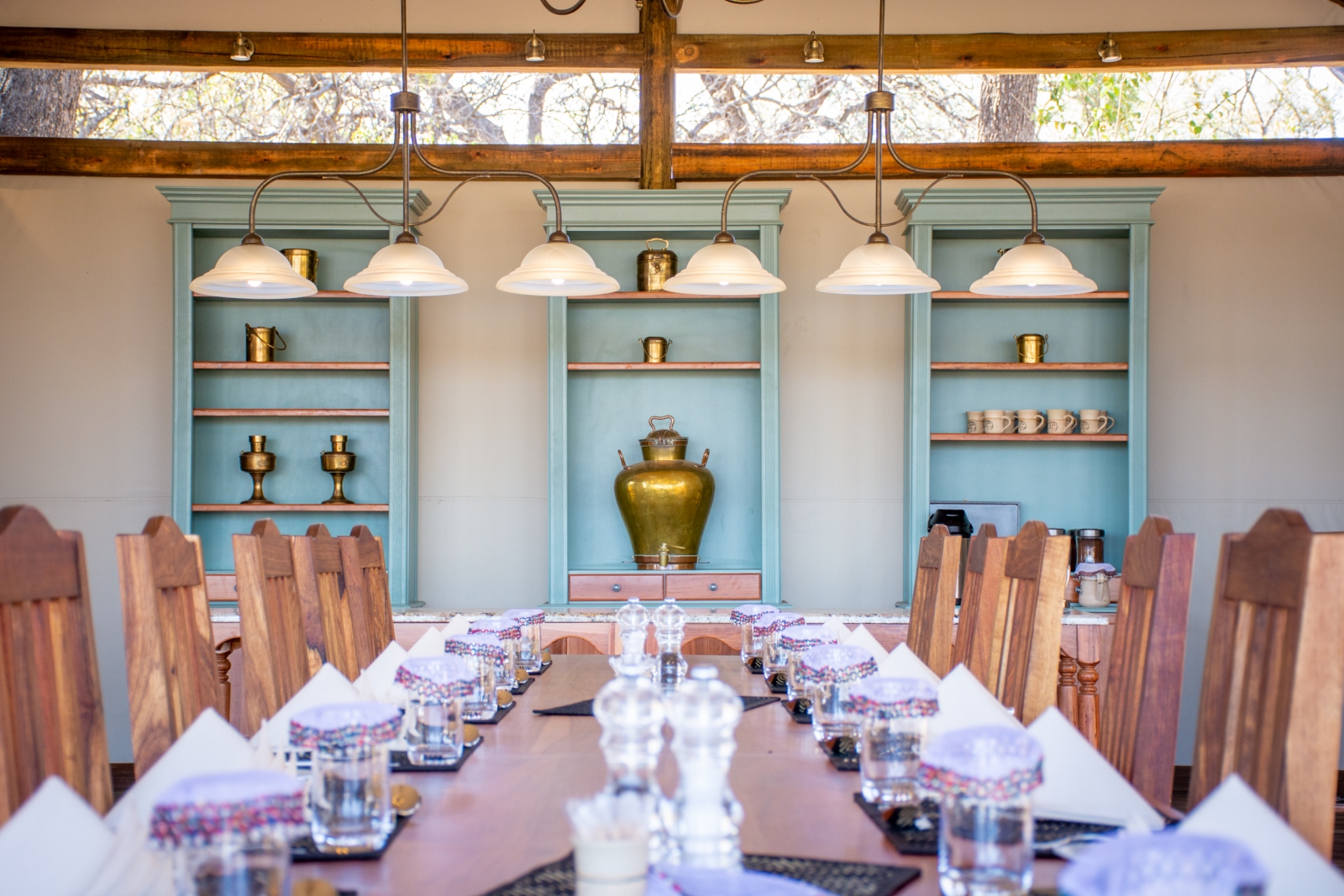 Big table set up for dinner infront of mint shelves
