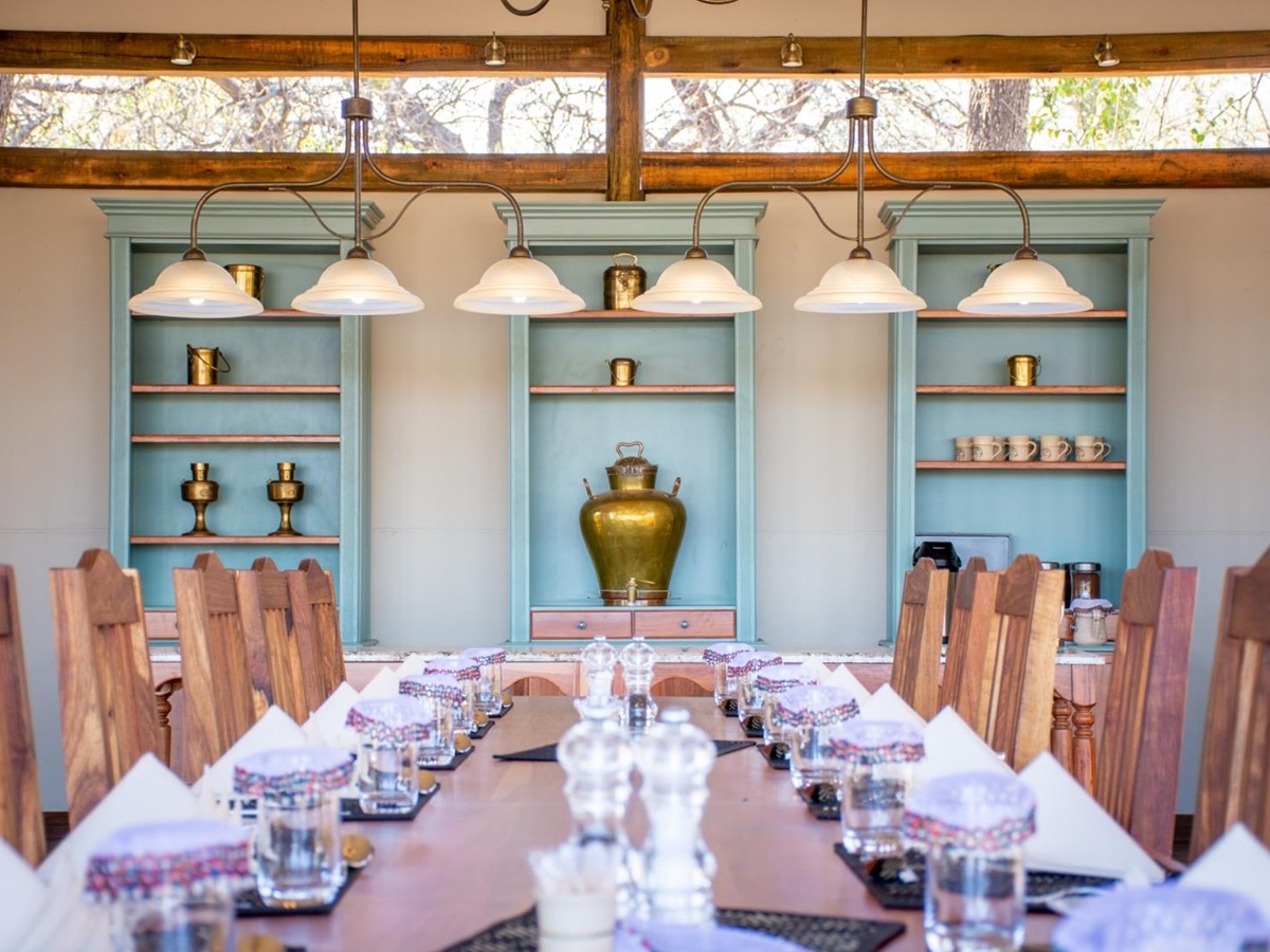 Big table set up for dinner infront of mint shelves