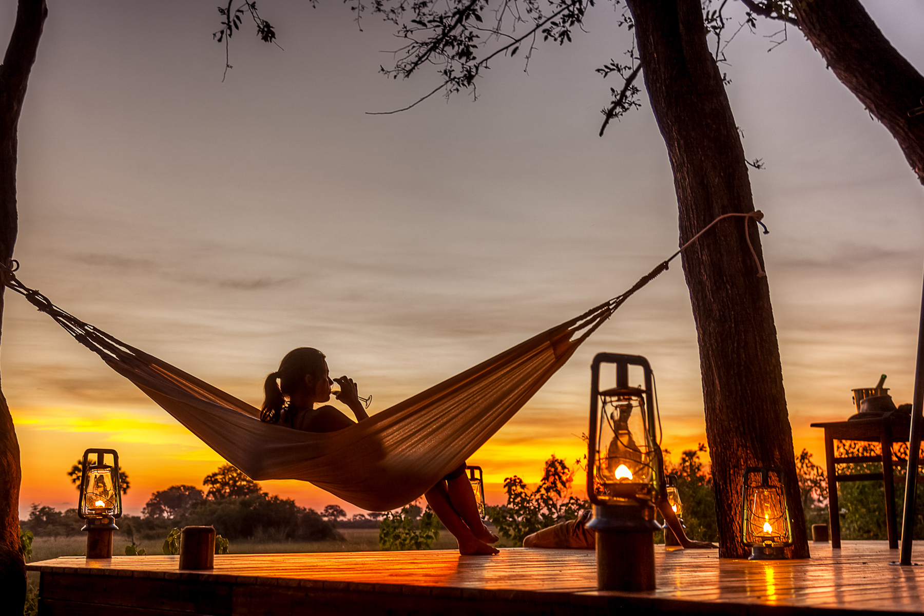 A woman on a hammock overlooking the Okavango Delta floodplains at Macatoo Camp