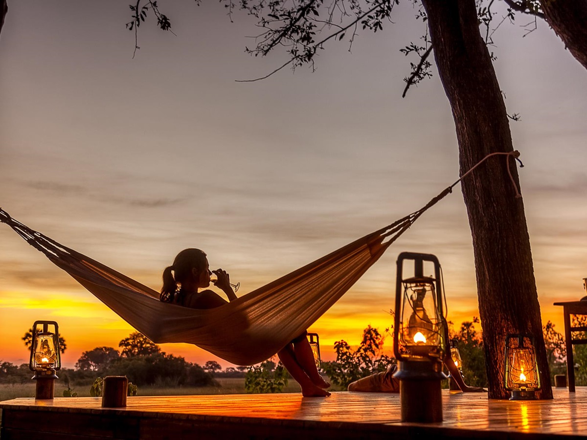 A woman on a hammock overlooking the Okavango Delta floodplains at Macatoo Camp