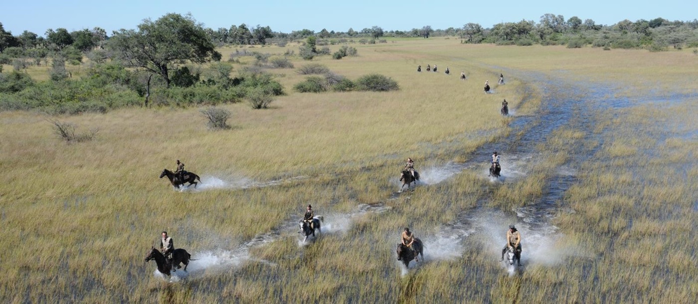 Aerial shot of group of people riding through the waters of the Okavango