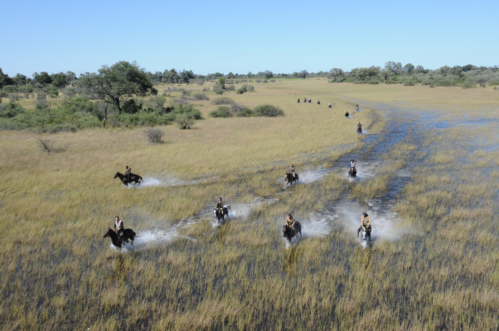 Aerial shot of group of people riding through the waters of the Okavango
