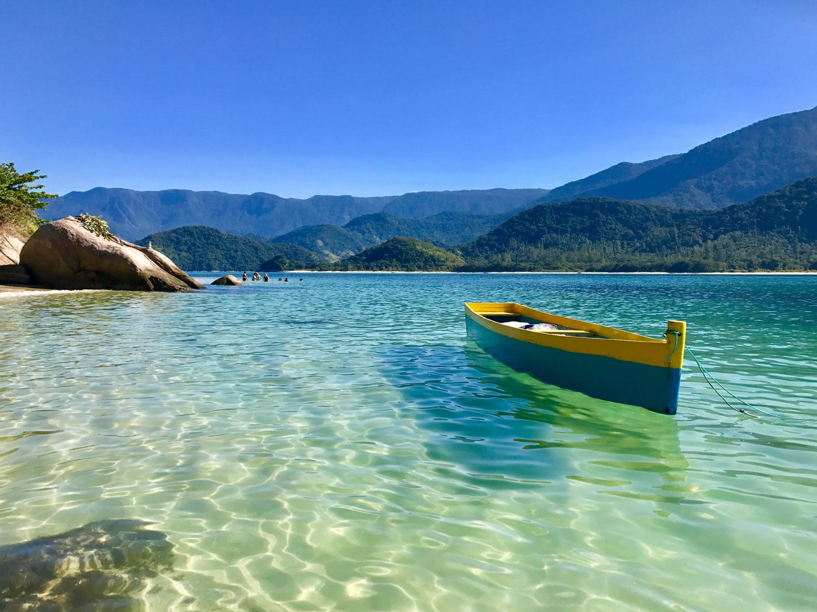 Crystal clear waters and wooden boat at a beach in Paraty, Brazil 