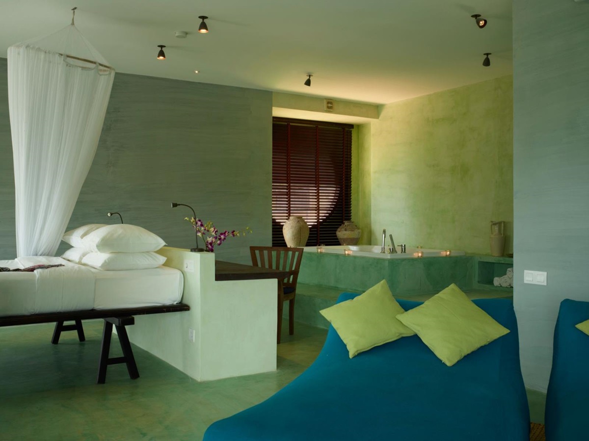 Green guest suite guestroom with bed and bathtub at Knai Bang Chatt resort in Cambodia