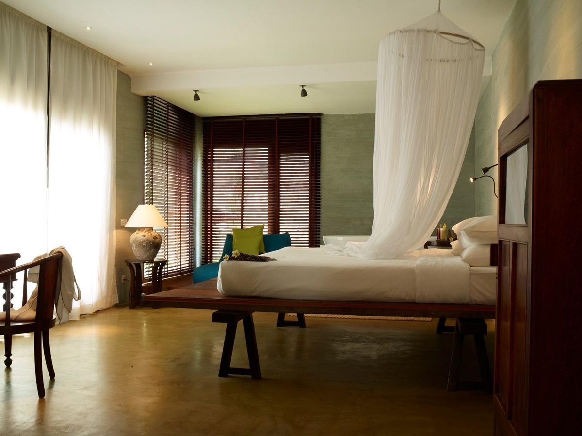Guest suite bedroom with shuttered windows at Knai Bang Chatt resort in Cambodia