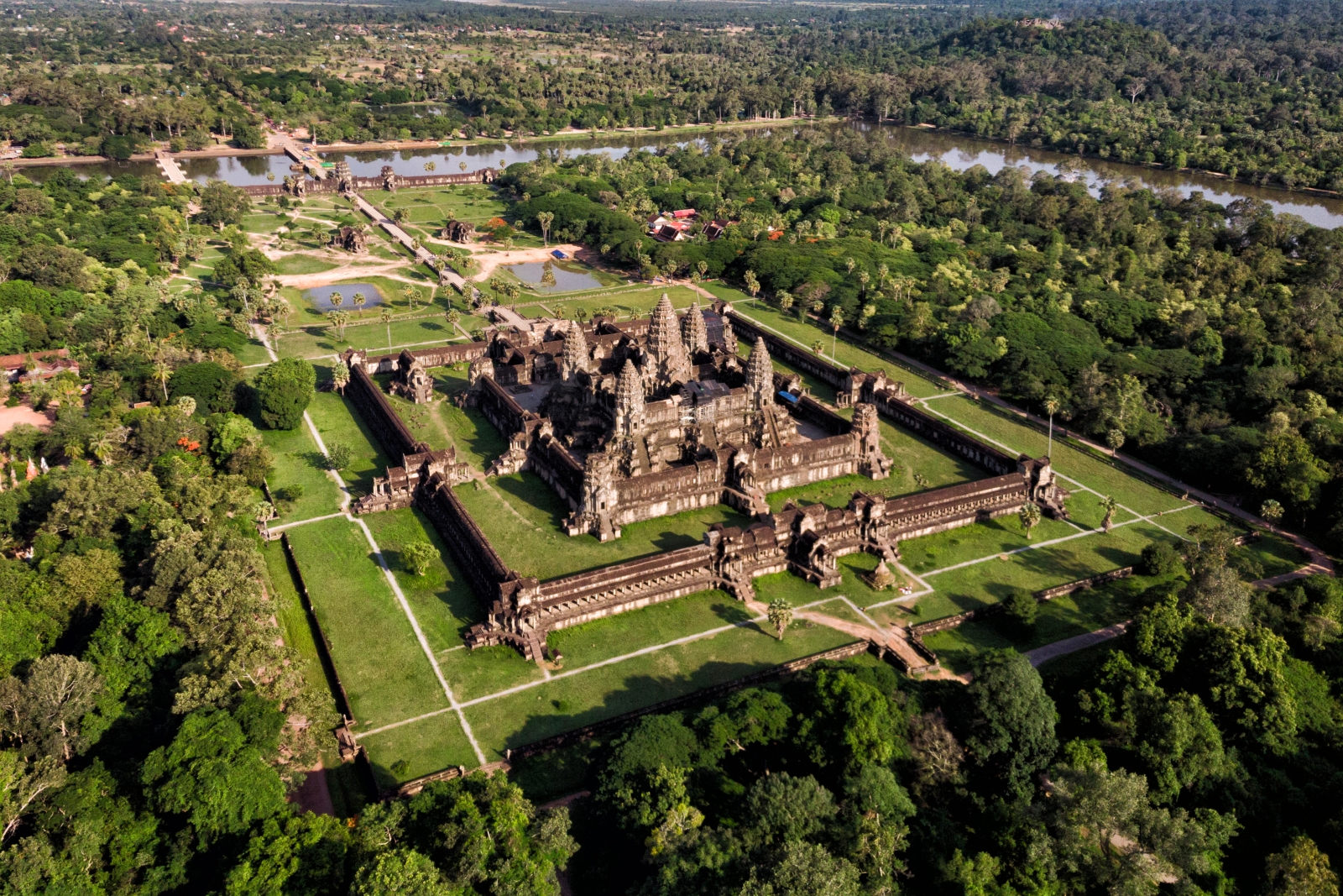 Aerial of grand square temple with stupas surrounded by grass and trees