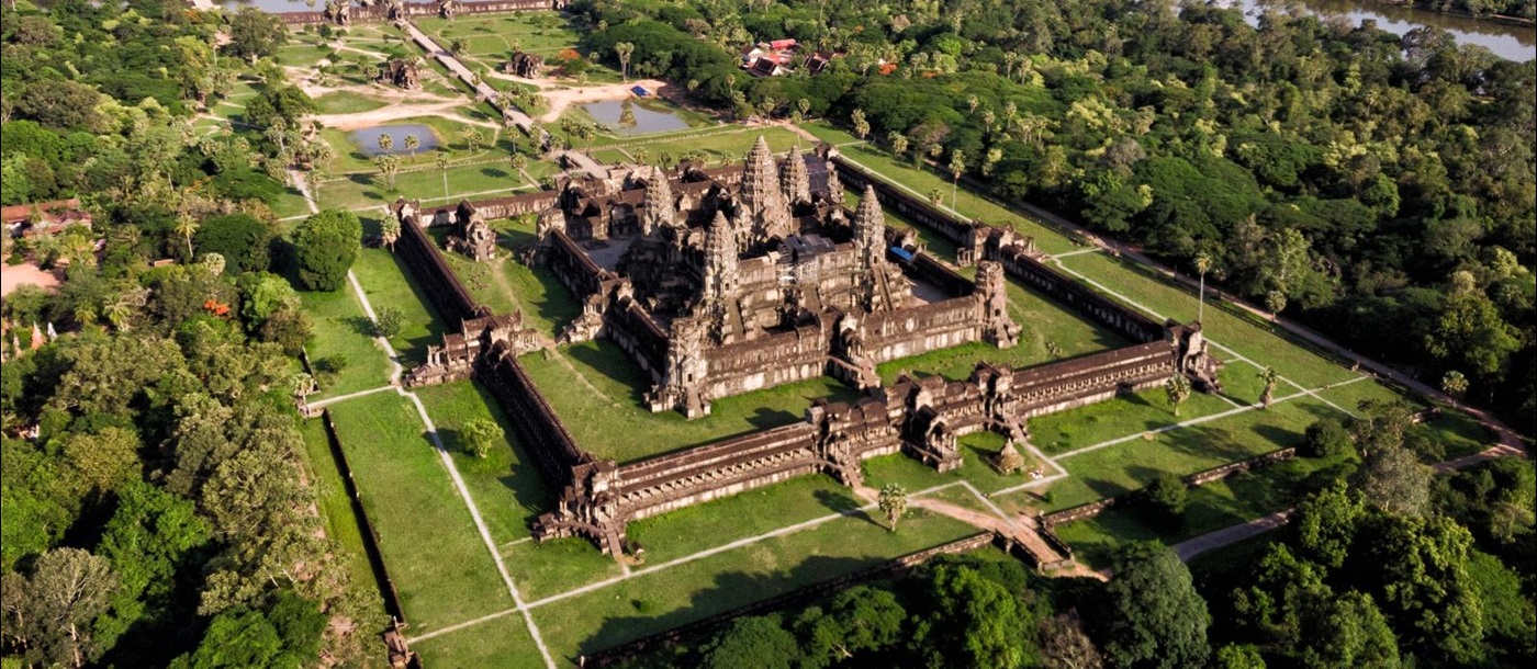 Aerial of grand square temple with stupas surrounded by grass and trees