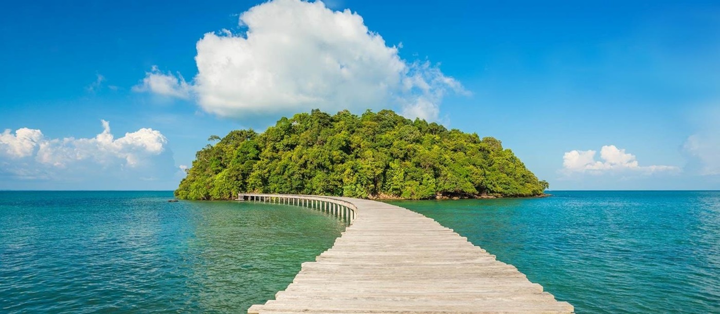 Wooden jetty leads to lush green island