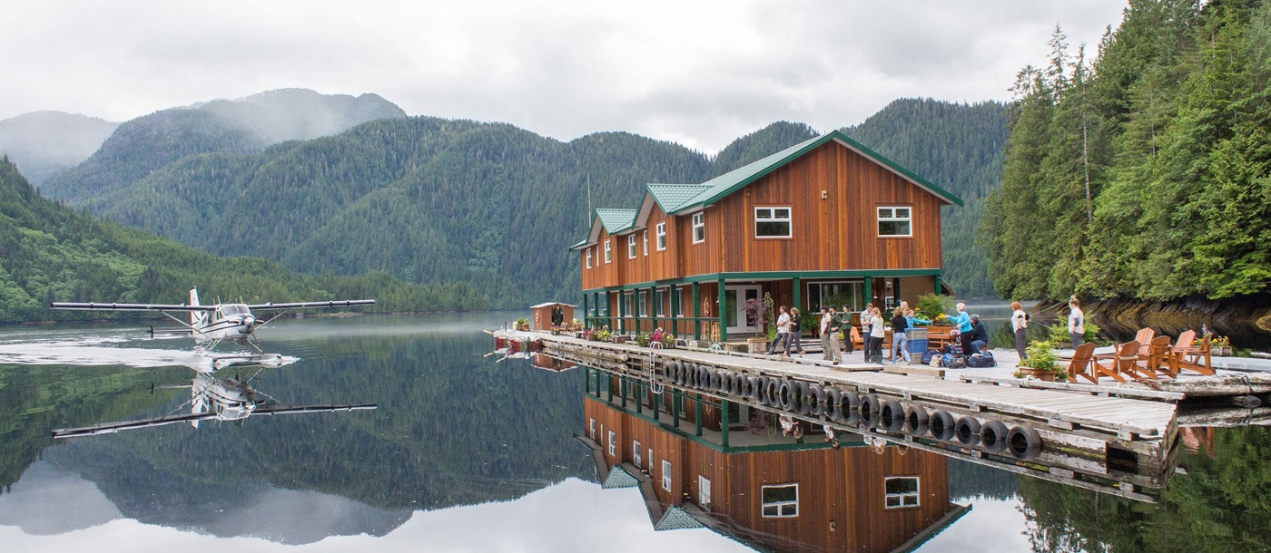 Seaplane Lodge with mountains in background reflecting in water, Great Bear Lodge, Canada